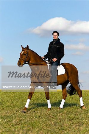 Young man riding a horse in the fields by the countryside