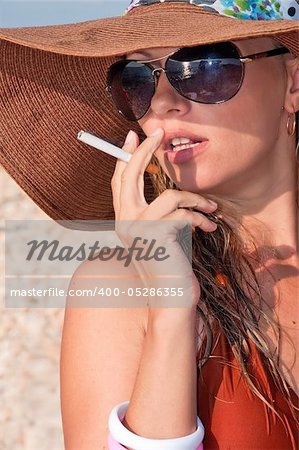 beautiful woman in a hat and sunglasses on the beach in a bikini