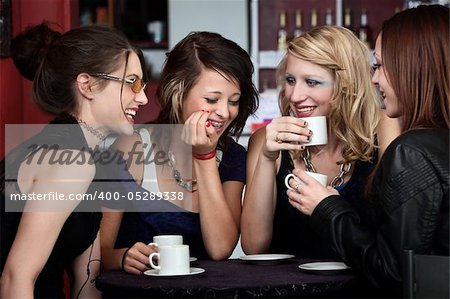 A foursome of pretty girls laughing in a cafe