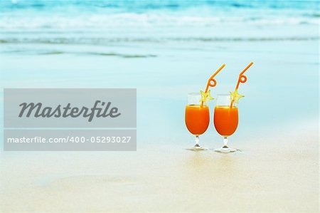 Two glasses of orange juice on tropical beach