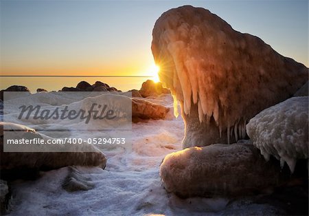 stones at the beach filled with ice at sunrise