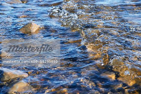 Surf on a seashore. Clean water and stony bottom