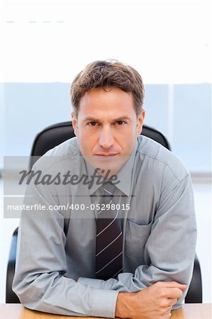 Serious manager sitting at a table in an office