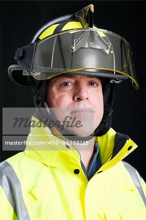 Head and shoulders portrait of a serious firefighter.  Studio shot on black background.