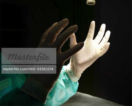Surgeon holding up hands in protective gloves photo