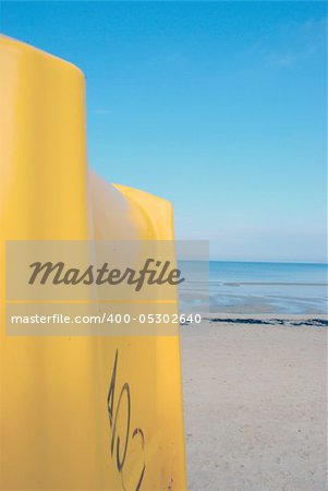 big yellow dustbin in background of blue still sea and sky