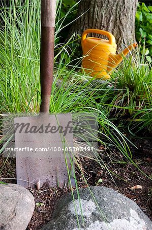 Close up of garden shovel with watering can in the background