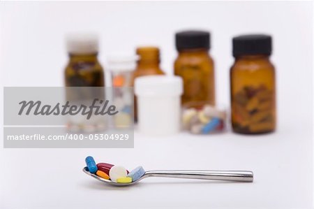 differently colored pills in spoon with other pills on the background differently colored pills in spoon with other pills on the background