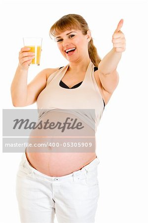 Smiling pregnant woman holding glass of juice and showing  thumbs up gesture isolated on white