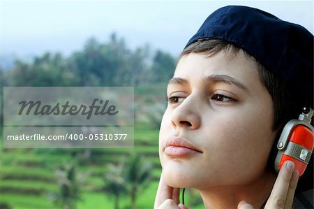 Boy with headphone in front of tropical background