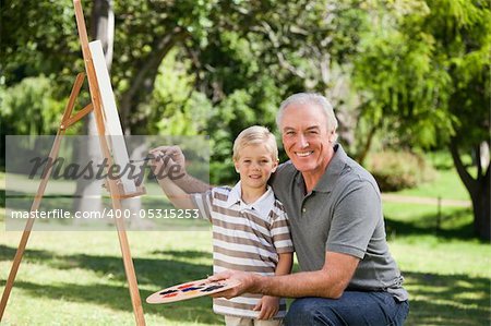 Happy Grandfather and his grandson painting in the garden