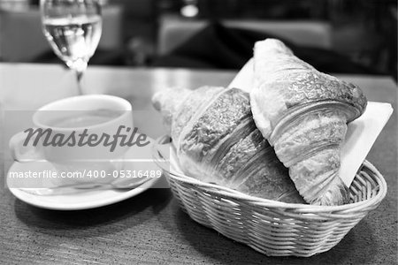 Breakfast with coffee and croissants in a basket on table