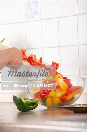 Female chopping food ingredients (paprika) on the kitchen.