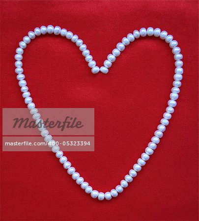 Heart from white pearls on an elegant red silk for St Valentine's day card