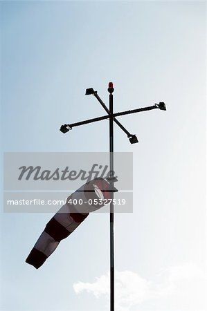 a red white striped wind gauge against cloudy sky