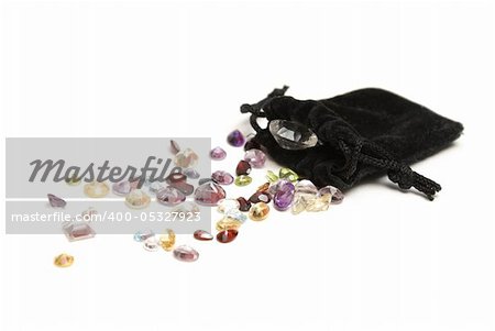 A spilled pouch of genuine gemstones of various colors and minerals.