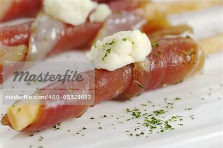 Appetizer: Bacon slice wrapped around salt stick with a piece of cheese on top (Selective Focus)