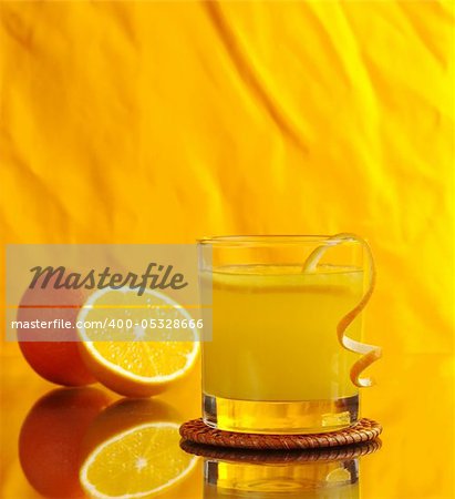 Fresh orange juice in glass with orange peel and oranges on orange background (Selective Focus)