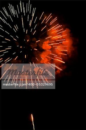 A burst of orange-red fireworks against a night sky.