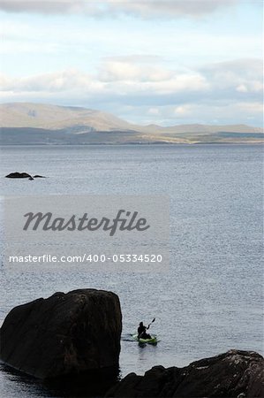 a lone green kayaker on the coast of kerry in ireland
