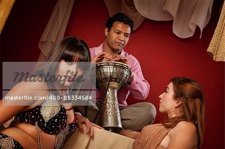 Two beautiful belly dancers with handsome Indian tabla player