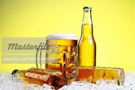 Bottles and Glass of beer with foam over yellow background