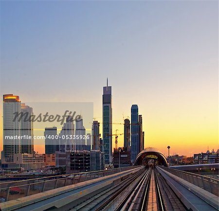 Modern city at sunset, metro overpass with rails, Dubai city in United Arab Emirates