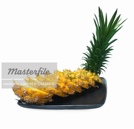 pineapple sliced on a black plate isolated on white background