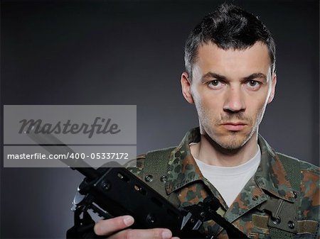 portrait of soldier in camouflage and ammunition with a rifle. studio shot