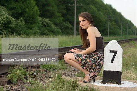 Young pretty girl near railroad's traffic sign. expression positive.