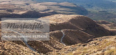 Twisting hilly track from mountain down to hut on sunset