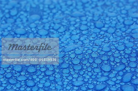 Closeup view of water drops on a blue fabric background