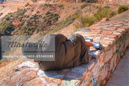 Homeless vagrant resting on a stone wall