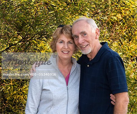 A happily married senior couple smiling and looking at camera as they embrace.