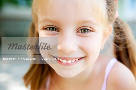 cute little girl smiling in a park close-up