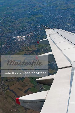airplane wing detail, flying over countryside, vertical composition
