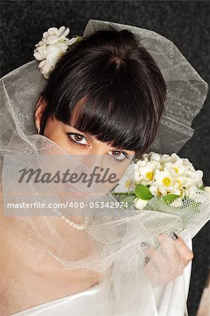 bride with a bouquet it covered face by the veil