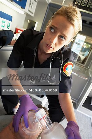 Paramedic holding oxygen mask over patient's face