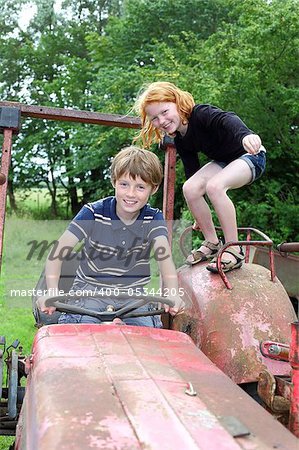 Two children playing on an old tractor