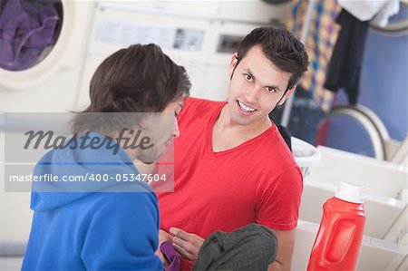 Handsome Latino and Caucasian men talk in a laundromat