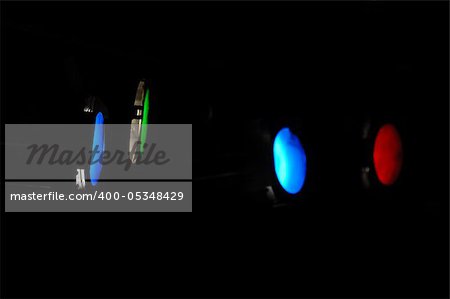 Spotlights on a dark background. The main focus is on the blue spotlight next to the green.