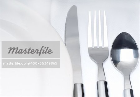 close up of a cutlery set on a table with napkin and dish