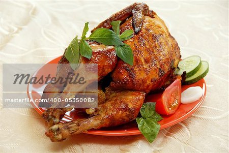 whole grilled chicken served on red plate decorated with vegetables and mint