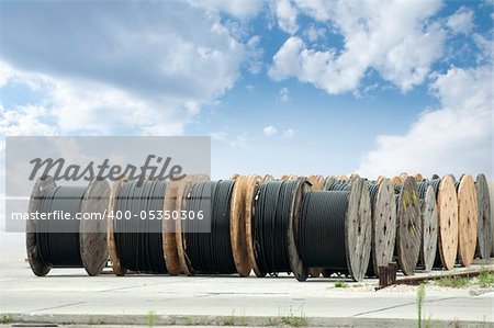 Large rolls of black cables on blue sky background