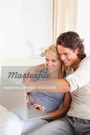 Portrait of a man showing something to his wife on a notebook in their living room
