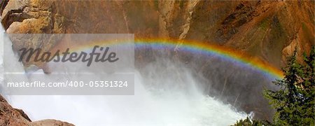 Sunlight creates a rainbow in mists of the Lower Falls of the Yellowstone River in Wyoming.