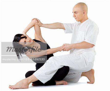 Young female sitting and receiving traditional thai arm stretching massage by therapist, isolated on white