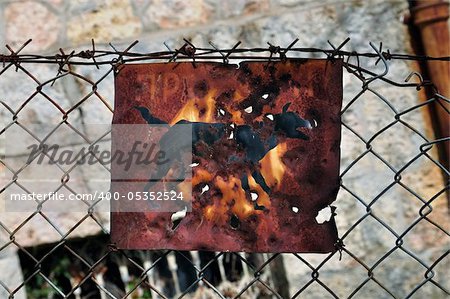 Rusty beware of the dog sign and chain link fence background.