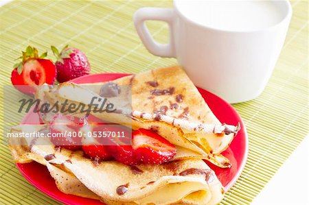 sweet pancakes with strawberry and cup of milk on white background