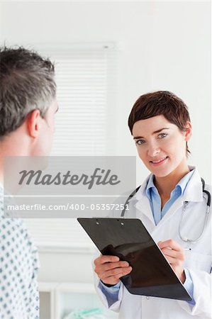 Doctor talking to a male patient while holding a chart in a room